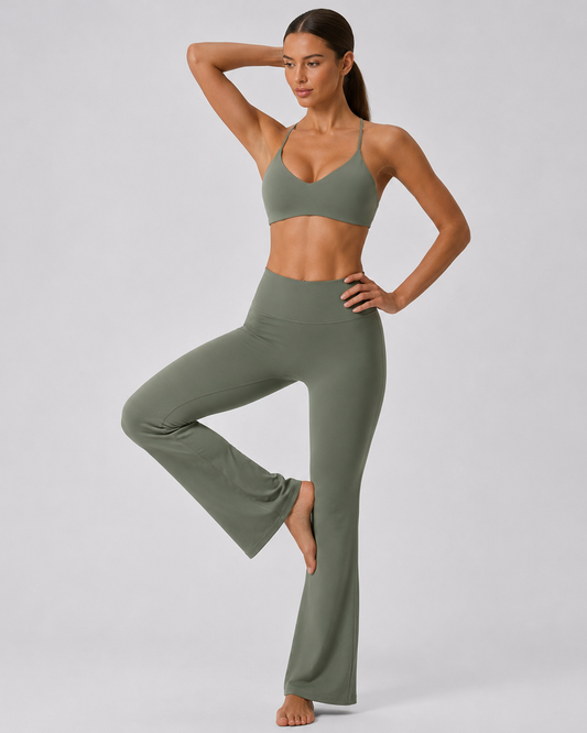 A woman modeling a matching olive green activewear set consisting of a sports bra and high-waisted flared leggings, posed against a light gray studio background.